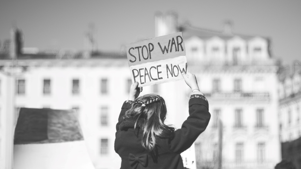 Kvinne sett bakfra med skilt der det står "Stop war - peace now"