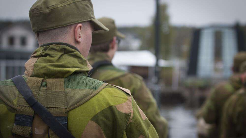 Soldater på rekke, nærbilde av en av soldatene som ser skrått til siden. Flere soldater i bakgrunnen. 