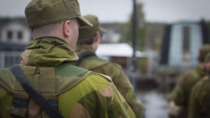 Soldater på rekke, nærbilde av en av soldatene som ser skrått til siden. Flere soldater i bakgrunnen. 